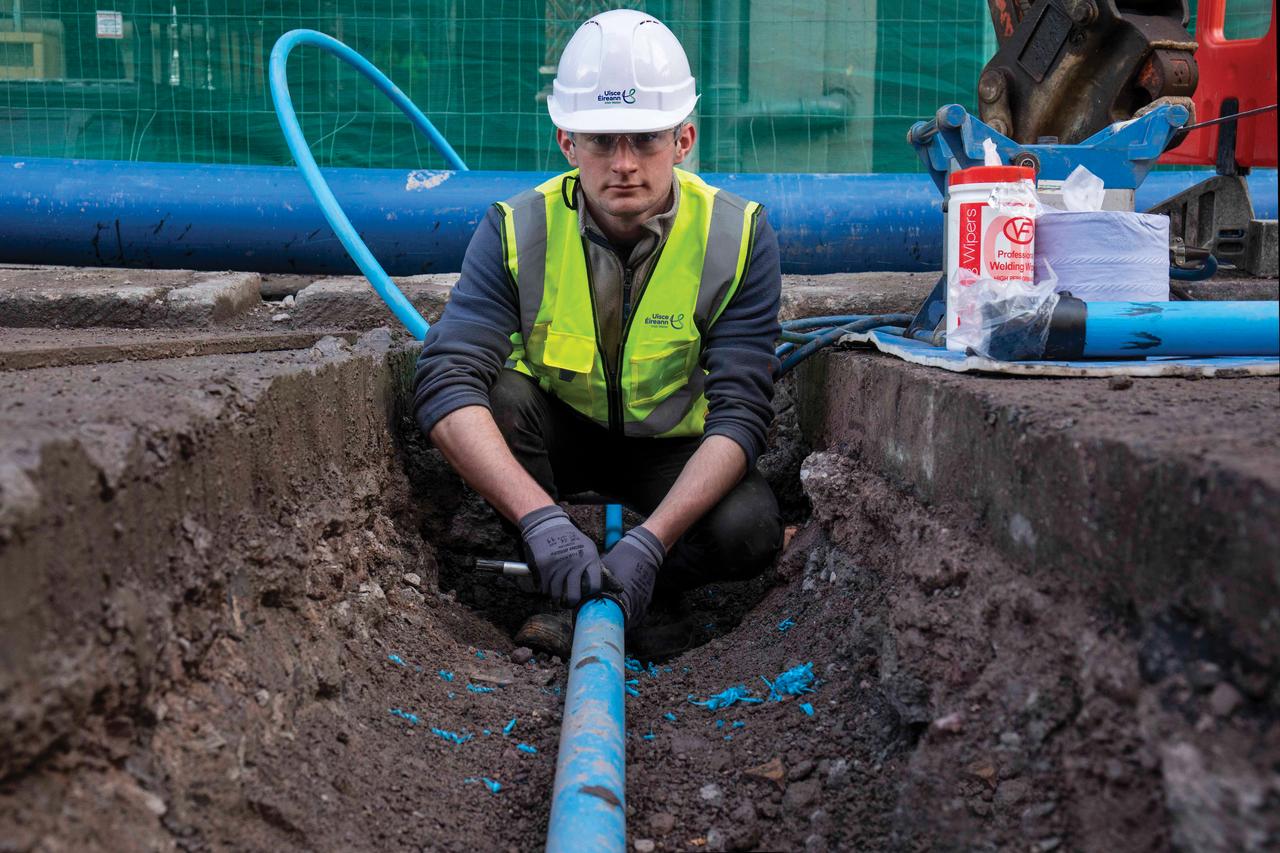 An engineer working on a pipe wearing a safety gear looking at the camera