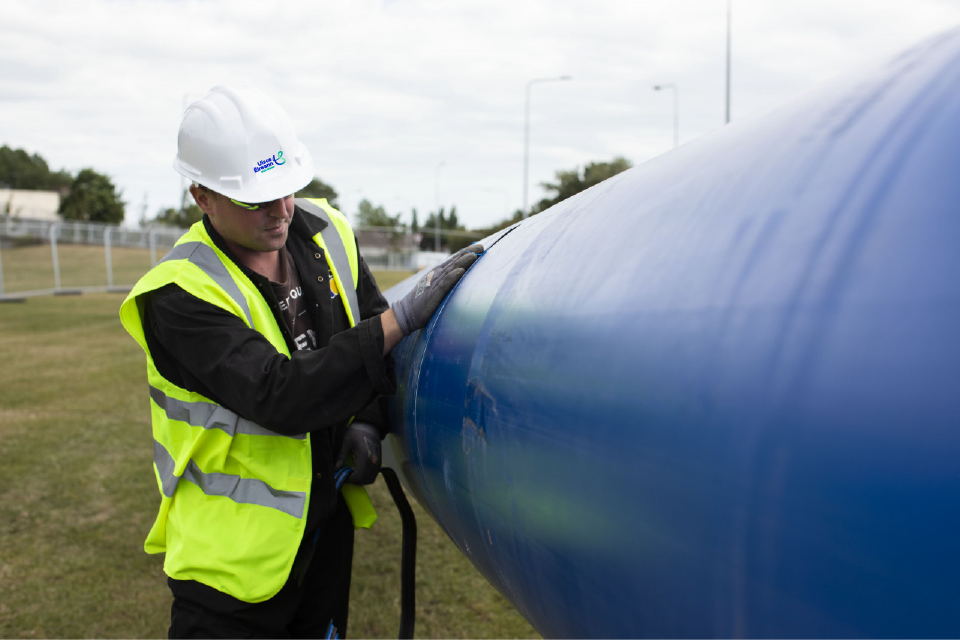 An Uisce Éireann worker working on a large blue pipe