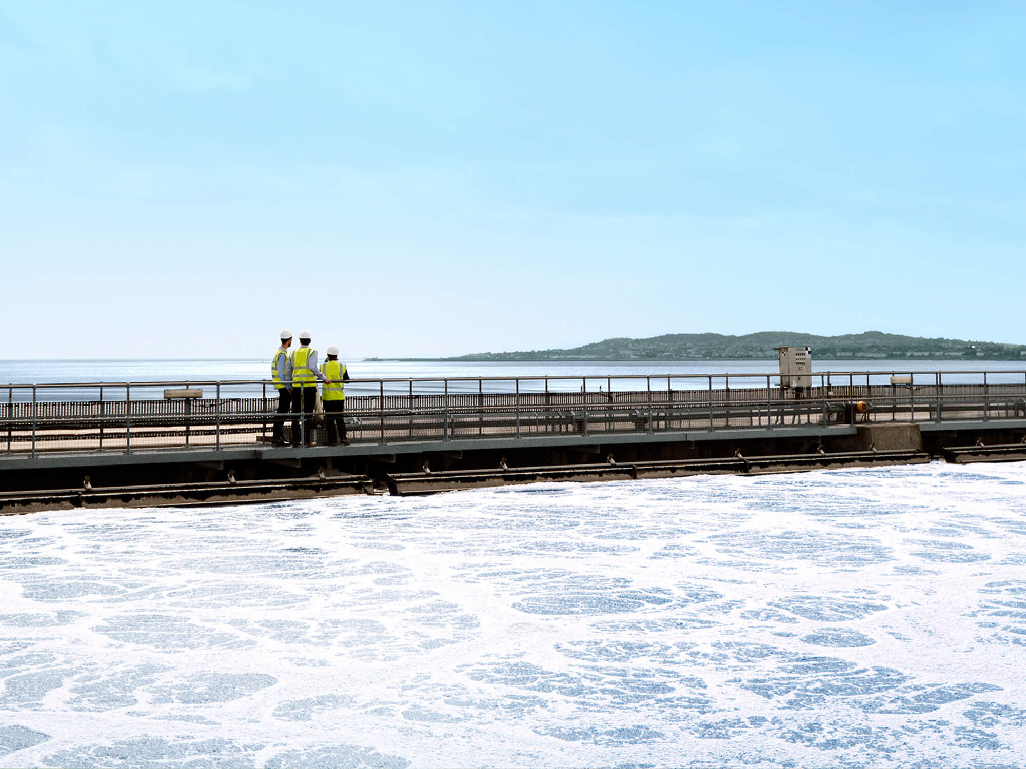 UÉ workers looking over the sea from a bridge