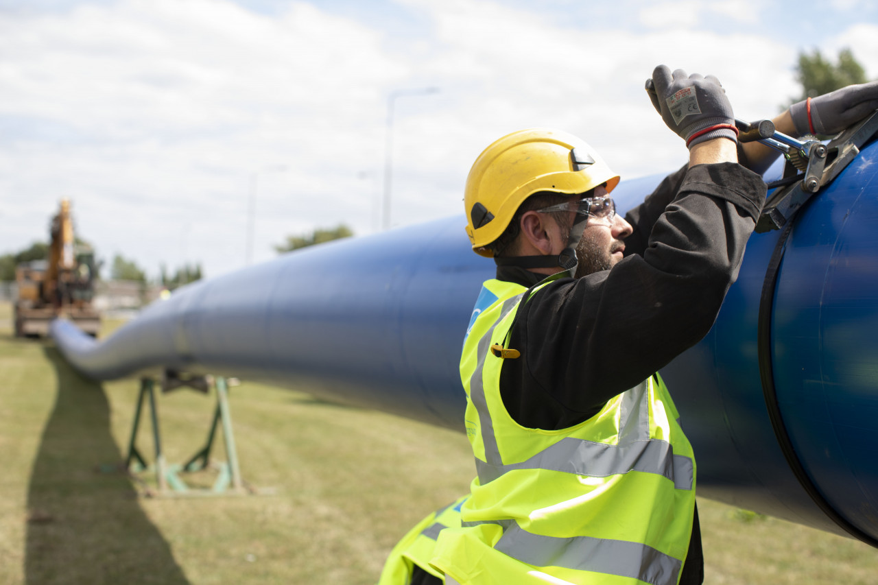An Uisce Éireann worker working on a large blue pipe