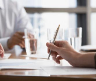 A hand holding a pen over papers on a table