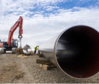 A large metal pipe on a construction site with a red digger truck