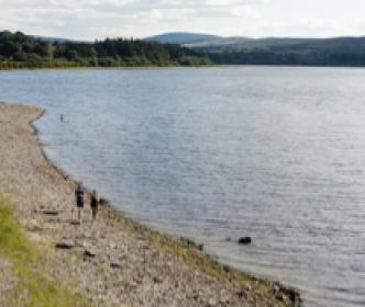 Two people walking on the edge of a lake