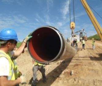 An Uisce Éireann worker with his hand on a large pipe on a construction site