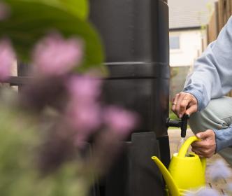 a woman pouring water into a watering can 