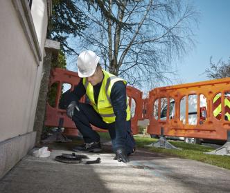 a uisce eireann worker kneeling down to look into a pipe 