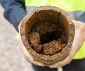 A worker holding an old rusty pipe