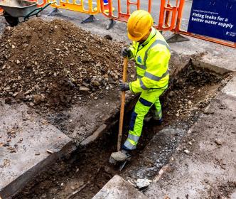 An Uisce Éireann worker digging a road with a shovel