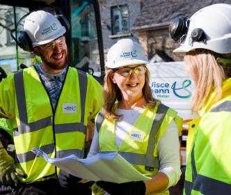 3 Uisce Éireann engineers holding site plans while smiling at eachother