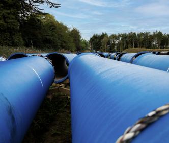 Several large blue pipes in a field