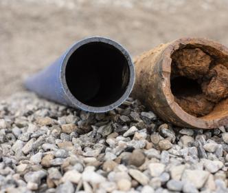 A new clean pipe next to an old damaged and rusty pipe