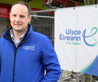 Enda MacNamara standing in front of a sign with the Uisce Éireann logo