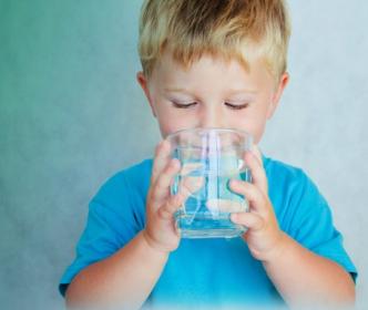A boy drinking a glass of water 