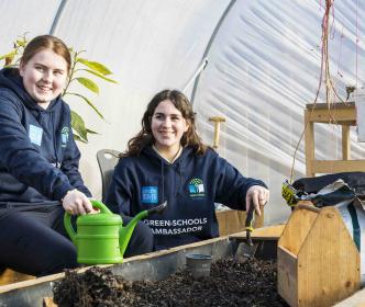Two Green-Schools ambassadors gardening in a greenhouse