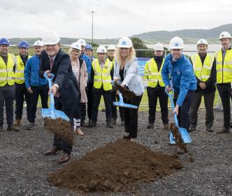 A group of people wearing hard hats with three people holding shovels