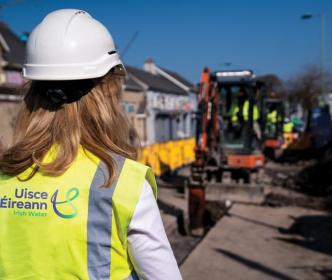 An Uisce Éireann worker on a roadworks site next to a white van