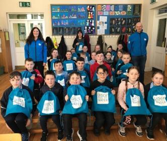 A group of schoolchildren holding Uisce Éireann bags