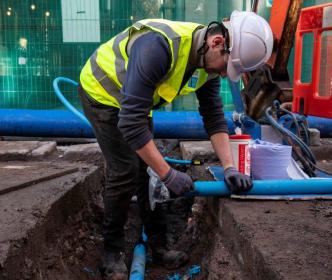 An Uisce Éireann worker working on a blue pipe