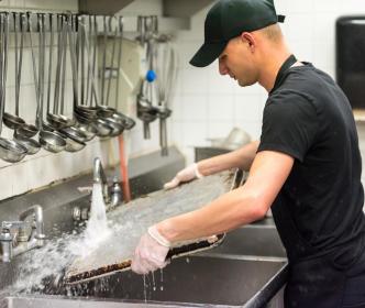 A man washing a tray in a kitchen sink