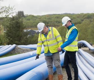 Uisce Éireann workers pointing at a large blue pipe