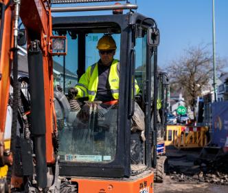 An Uisce Éireann worker in a digger on a roadworks site