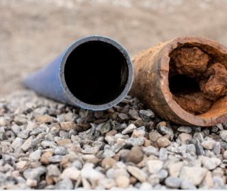 A new clean pipe next to an old damaged and rusty pipe