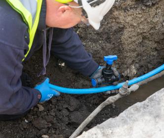 An Uisce Éireann worker fitting a new pipe in the ground