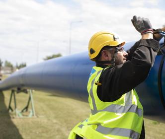 An Uisce Éireann worker working on a large blue pipe