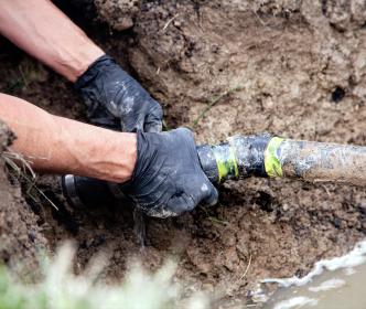A worker fixing a pipe in the ground
